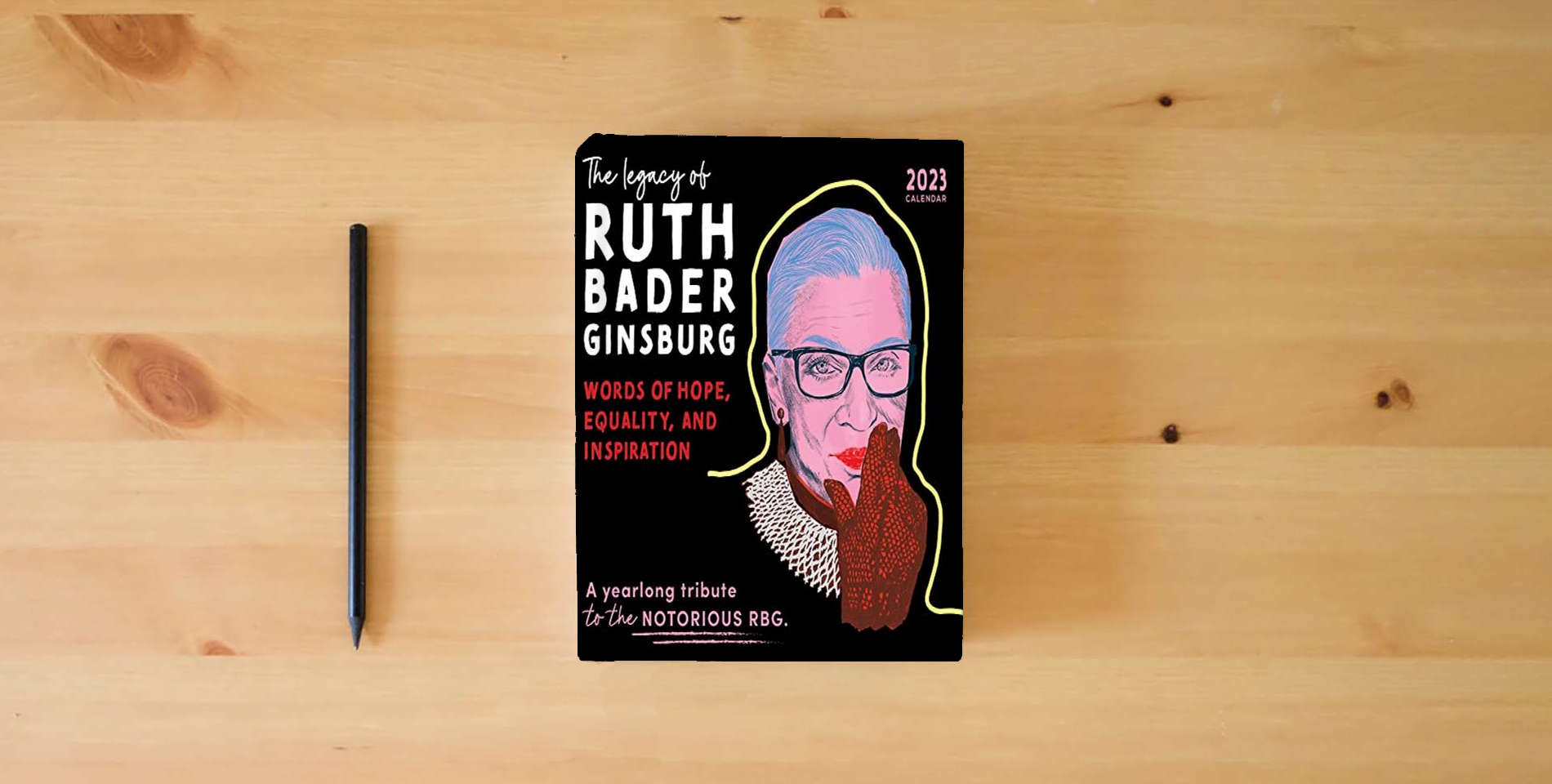The book 2023 The Legacy of Ruth Bader Ginsburg Wall Calendar: Her Words of Hope, Equality and Inspiration ― A yearlong tribute to the notorious RBG (12-Month Art Calendar) is on the table
