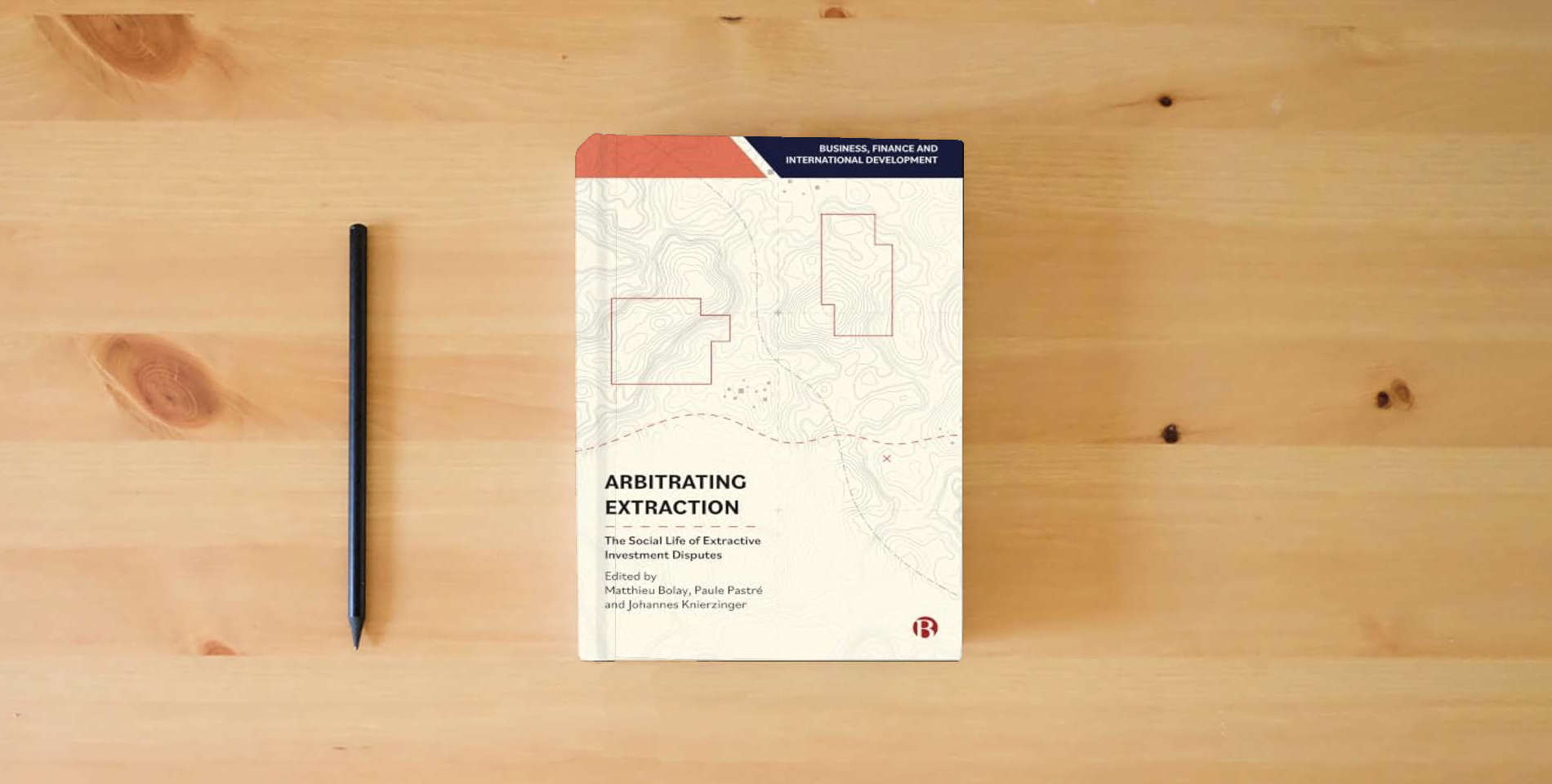 The book Arbitrating Extraction: The Social Life of Extractive Investment Disputes (Business, Finance and International Development) is on the table
