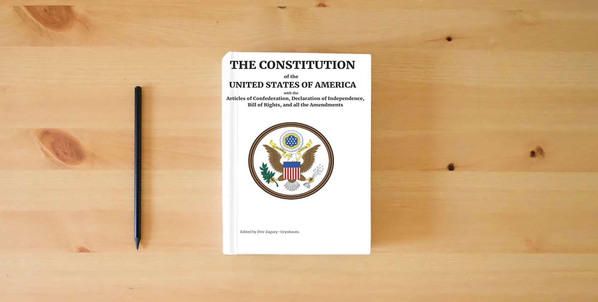 The book The Constitution of the United States of America: With the Articles of Federation, Declaration of Independence, Bill of Rights, and all the Amendments - Edited by Dvir Zagury Grynbaum is on the table