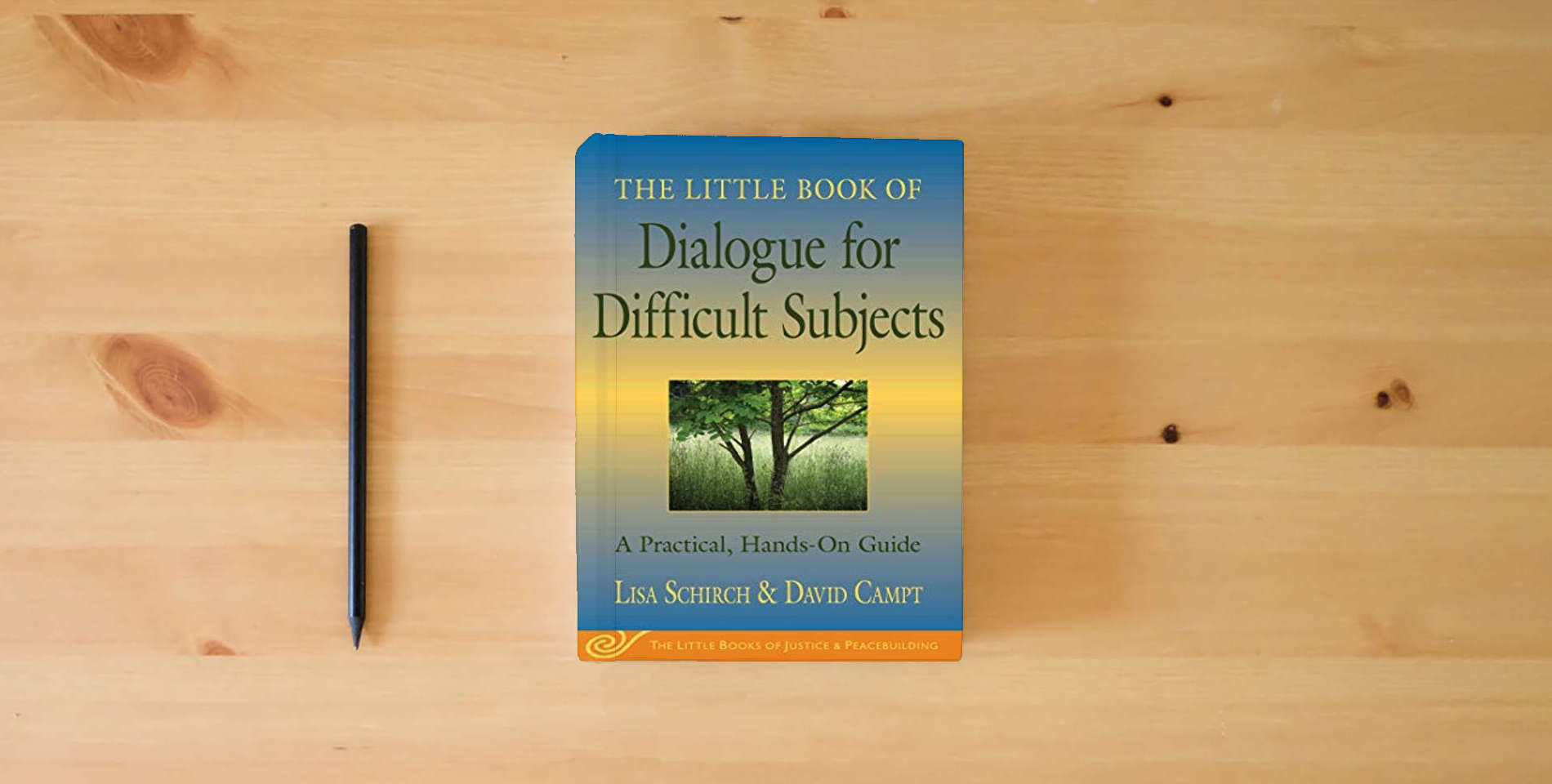 The book The Little Book of Dialogue for Difficult Subjects: A Practical, Hands-On Guide (Justice and Peacebuilding) is on the table