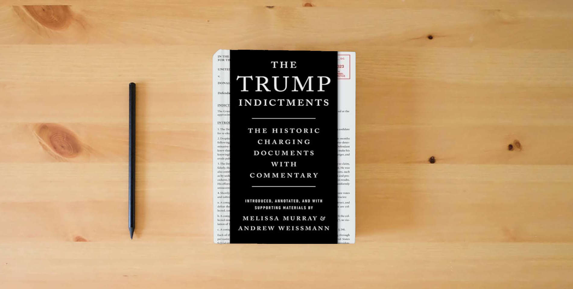 The book The Trump Indictments: The Historic Charging Documents with Commentary is on the table