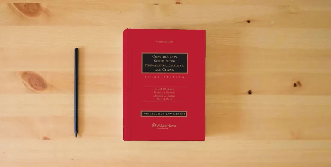 The book Construction Scheduling: Preparation Liability & Claims 3e} is on the table