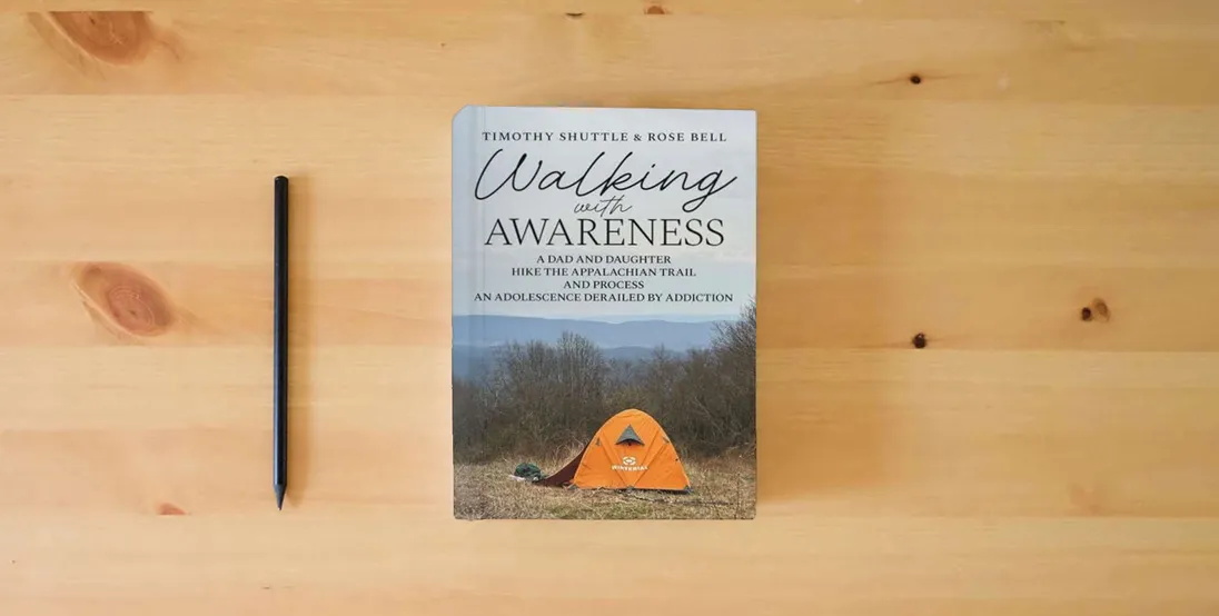 The book Walking with Awareness: A Dad and Daughter Hike the Appalachian Trail and Process an Adolescence Derailed by Addiction} is on the table